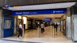 Entrance to Queen Street Bus Station beneath Queen Street Mall in Brisbane CBD with TransLink signage and commuters walking inside.