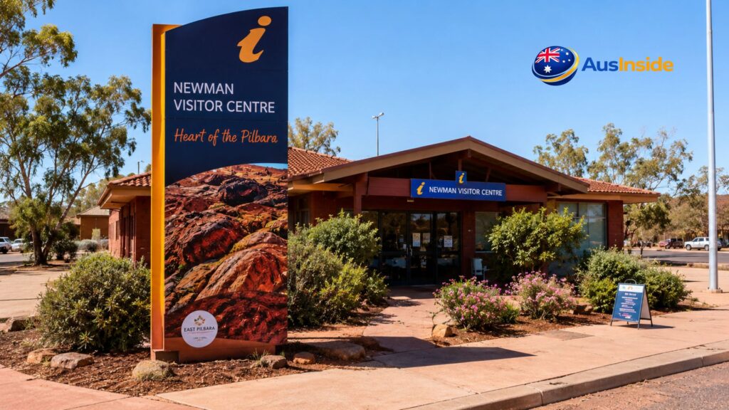 Front entrance of Newman Visitor Centre in Western Australia, featuring the iconic visitor information sign, landscaped gardens, and a clear blue Pilbara sky.