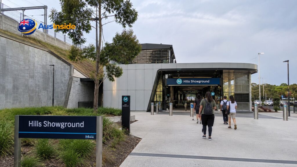 Hills Showground Station entrance in Castle Hill with commuters walking toward the modern Sydney Metro station on a cloudy day.