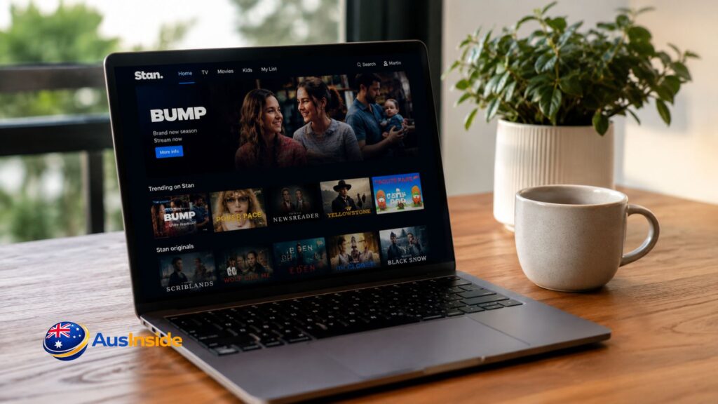 Laptop streaming Stan on a wooden table beside a coffee mug and indoor plant, showcasing popular Australian TV shows in a cozy home setting.