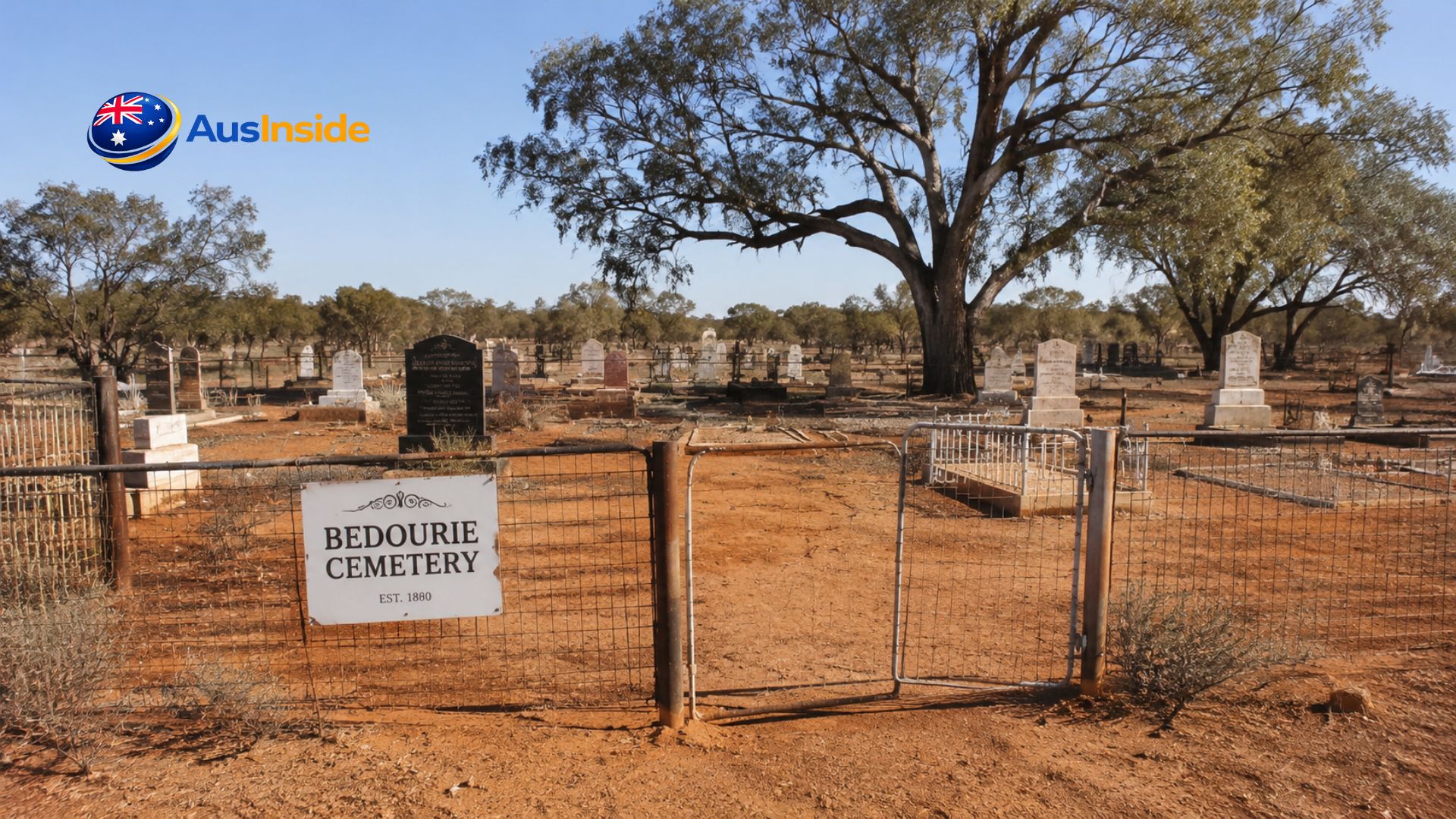 Bedourie Cemetery entrance with historic headstones, red outback landscape, and a large gum tree under a clear blue Queensland sky.