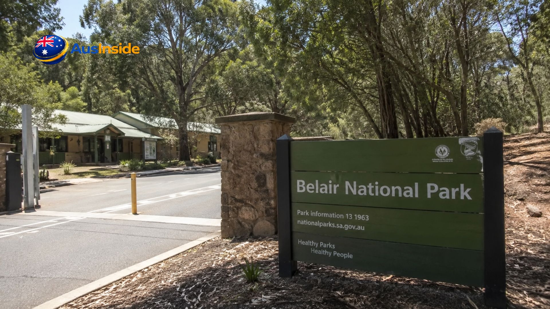 Belair National Park entrance sign with the visitor centre, road entrance, and tall eucalyptus trees on a sunny day in South Australia.
